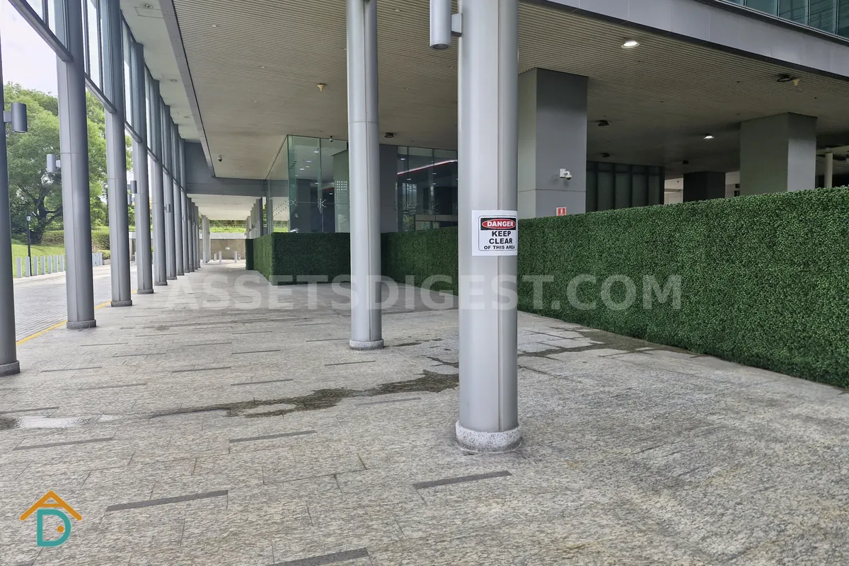 Covered pedestrian walkway beside a building podium, with a danger sign posted on a support column