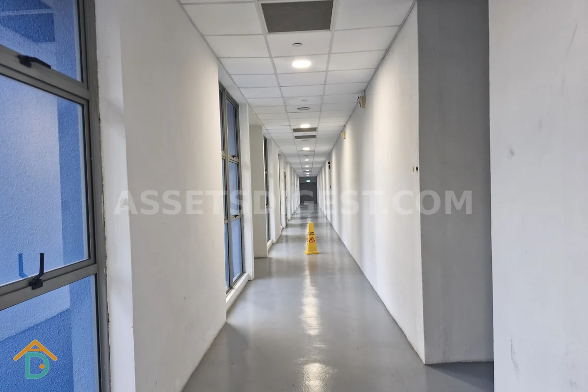 Interior corridor with unit doors and windows, a wet-floor caution cone placed in the walkway ahead